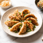 Gyoza au porc noir Berkshire dorés dans l'assiette, fond croustillant et sauce tare