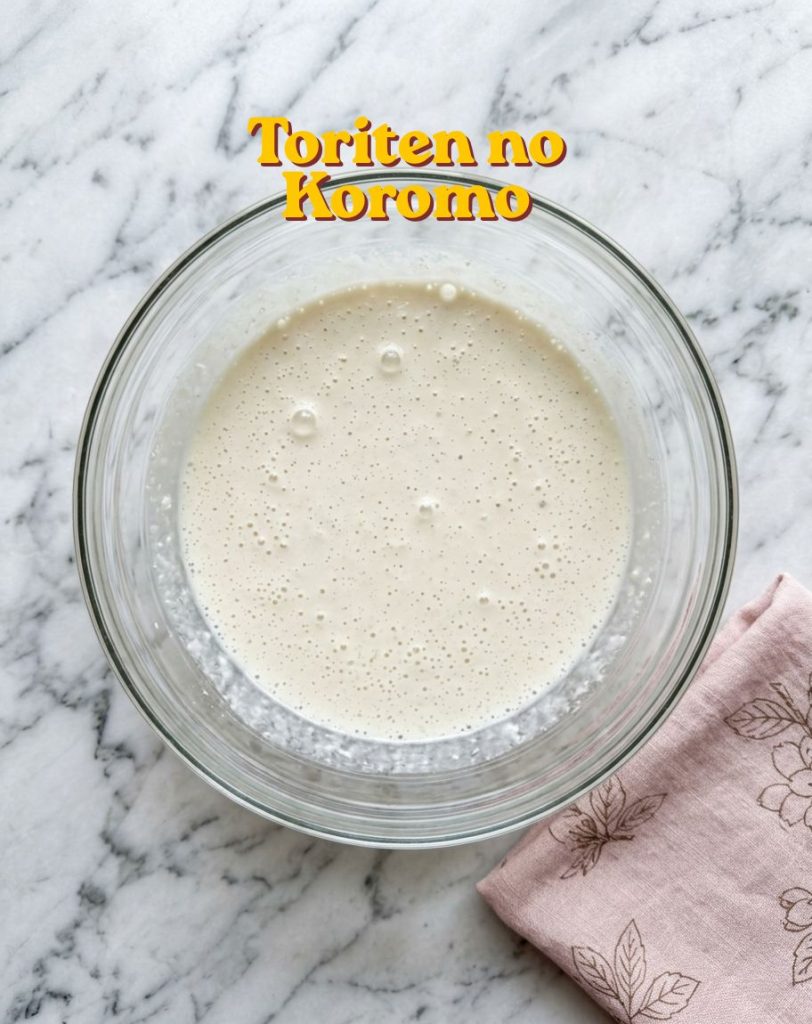 Recette Toriten : le Poulet en Tempura Traditionnel d'Oita 12 Pâte à toriten japonaise traditionnelle (Toriten no Koromo) dans un bol en verre, posé sur un plan de travail en marbre.