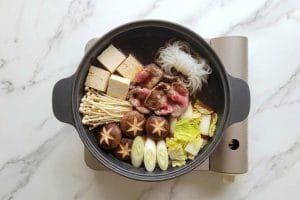 Cuisson de fines tranches de bœuf de 3 mm bien à plat dans le bouillon warishita du sukiyaki.