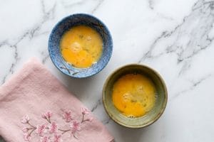 Deux petits bols en céramique contenant des œufs crus battus pour la dégustation traditionnelle du sukiyaki.
