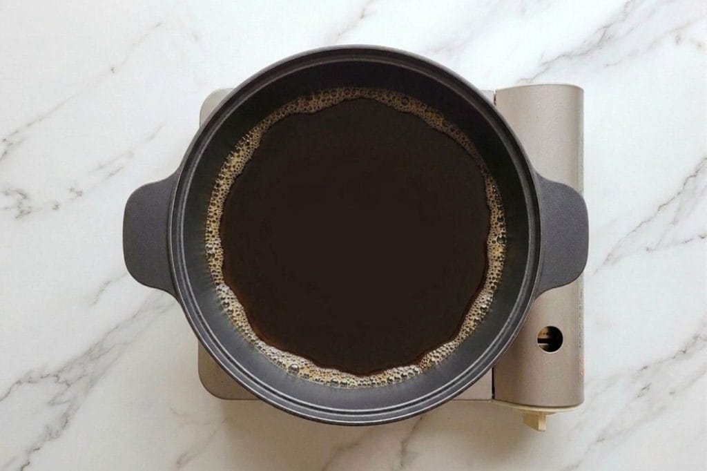 Shabu Shabu : Recette Authentique de la Fondue Japonaise 17 Sauce warishita qui frémit dans une marmite en fonte japonaise posée sur un réchaud.