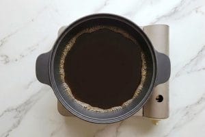 Sauce warishita qui frémit dans une marmite en fonte japonaise posée sur un réchaud.