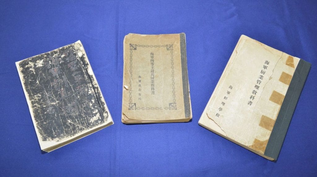 Les manuels de cuisine de la Marine impériale (1908-1938) exposés à Maizuru. Celui de 1938 (au centre) contient la première recette officielle du nikujaga actuel. / Crédit : Ville de Maizuru.