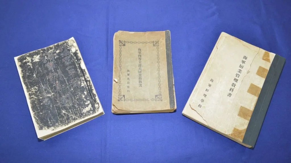 Les manuels de cuisine de la Marine impériale (1908-1938) exposés à Maizuru. Celui de 1938 (au centre) contient la première recette officielle du nikujaga actuel. / Crédit : Ville de Maizuru.