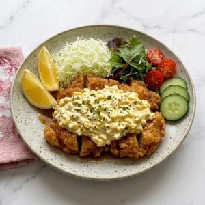 Poulet nanban (チキン南蛮) avec sauce tartare japonaise, dressé avec chou râpé, salade, tomates cerises, quartiers de citron et tranches de concombre