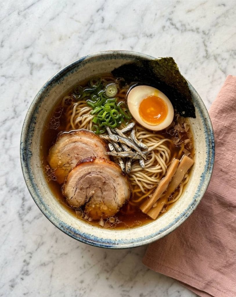 Bouillon Gyokai : la Recette du Dashi Marin pour Ramen 15 Le Niboshi Shoyu Ramen est une spécialité japonaise de ramen caractérisée par un bouillon mariant de la sauce soja (shoyu) et des petites sardines séchées (niboshi), ce qui lui confère une saveur marine unique riche en umami.